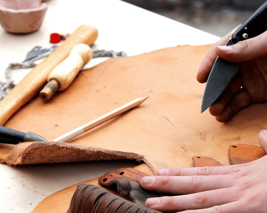 Person working with leather costume on a table with tools
